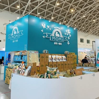 MOMI Animal Health — teal corner booth at a Taiwan pet exhibition with stacked product, logo wall, and floor display